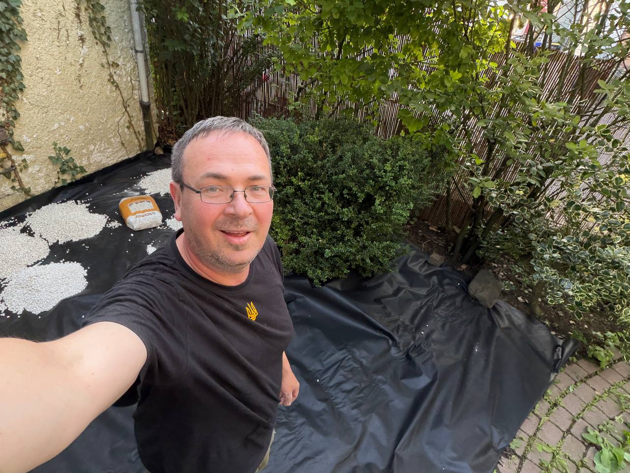 Gartenbeet halb fertig: Vlies liegt, weißer Kies wird verteilt