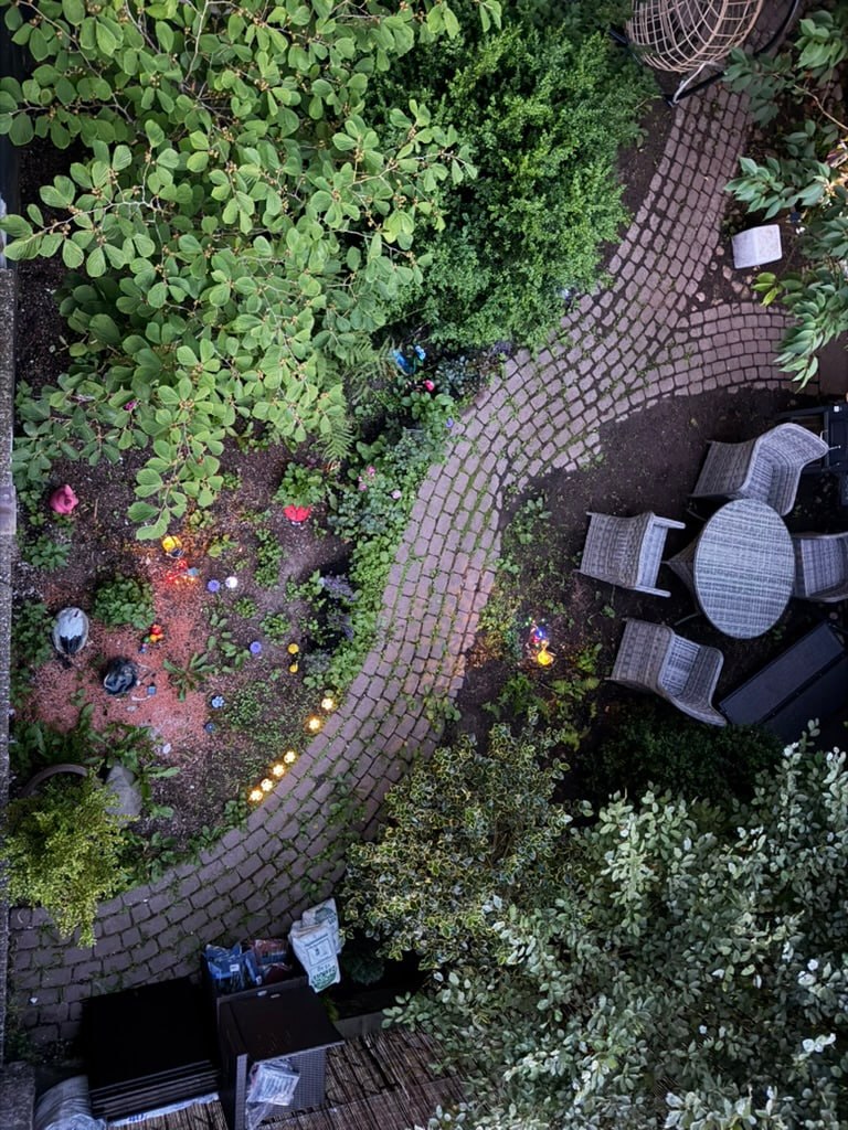 Kleiner gepflegter Garten mit Steinweg, Pflanzen und Lichterkette als gemütlicher Wohlfühlplatz