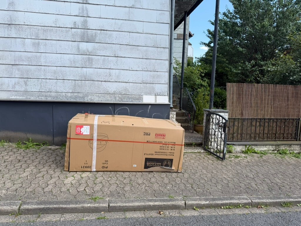 Sperrige Lieferkartonage der runden Gartenliege auf dem Bürgersteig – zu groß für den Gartenzugang