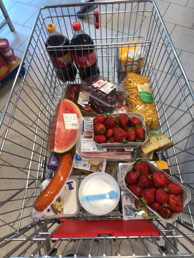 Einkaufswagen mit Lebensmitteln im Supermarkt – realer Wocheneinkauf einer Familie