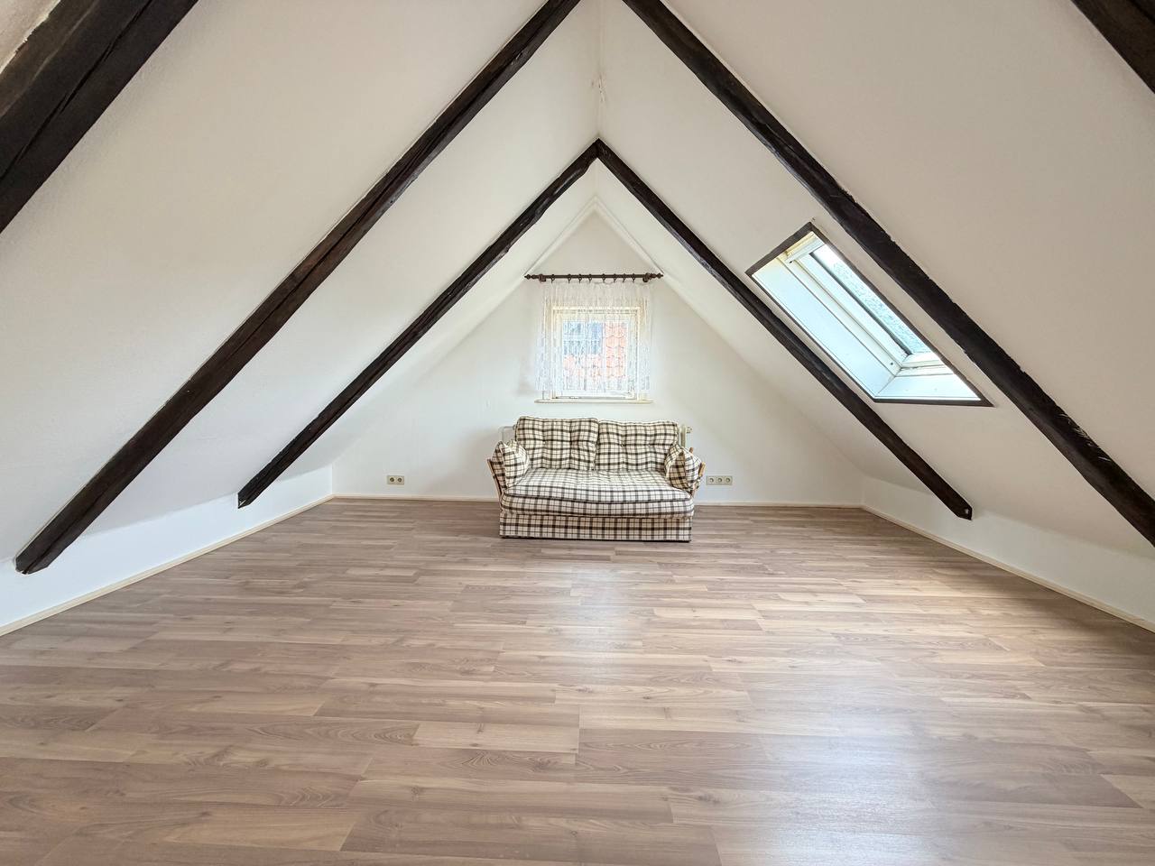 Ausgebauter Dachboden mit Holzbalken, Laminat, Dachfenster und Sofa – 80 m² Eigenleistung