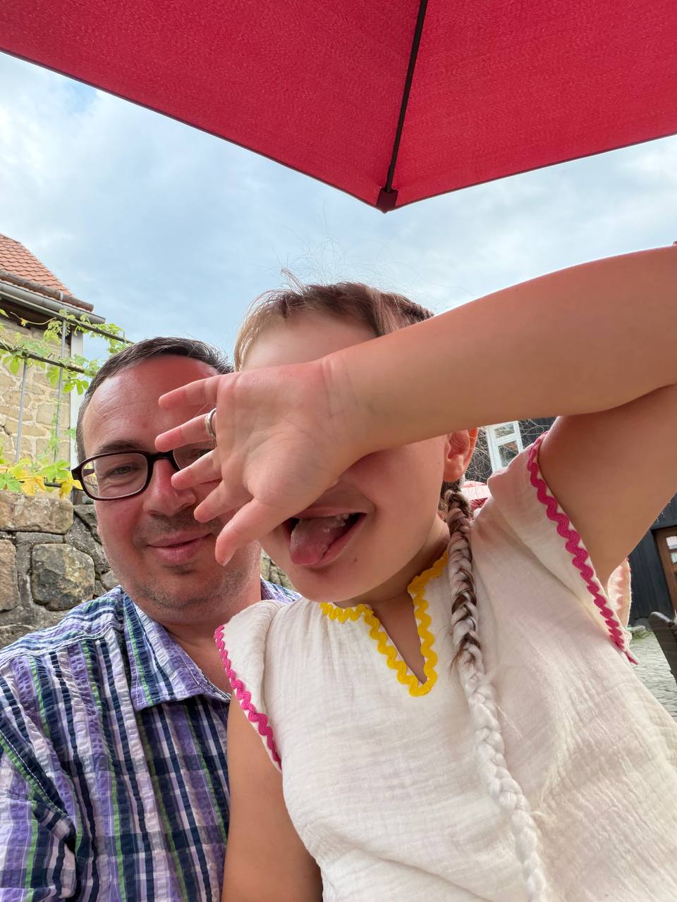 Vater und Tochter lachen unter einem roten Sonnenschirm – Ikigai Moment